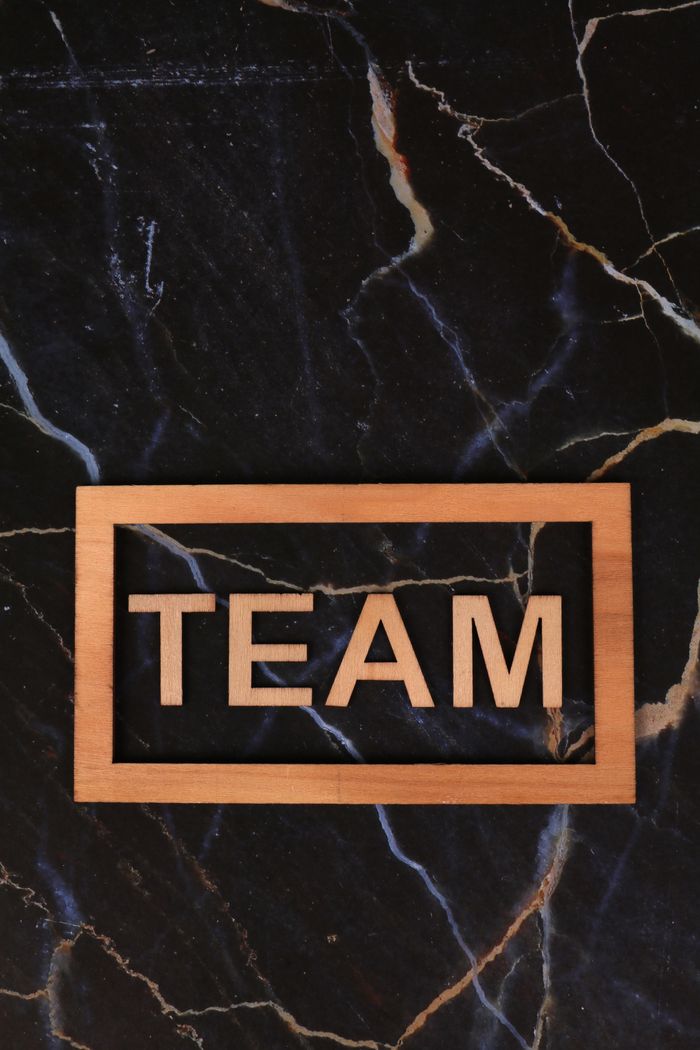 Wooden frame spelling 'TEAM' on a black marble surface, symbolizing collaboration.